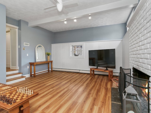 living room featuring ceiling fan, beam ceiling, stairs, light wood-type flooring, and visible vents