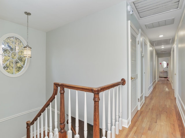 hallway with attic access, baseboards, an upstairs landing, light wood-type flooring, and visible vents