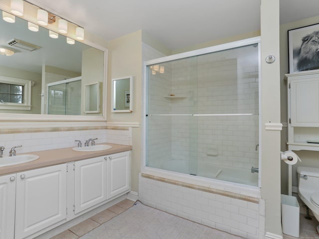 bathroom featuring a sink, tile patterned floors, tiled shower / bath, and toilet