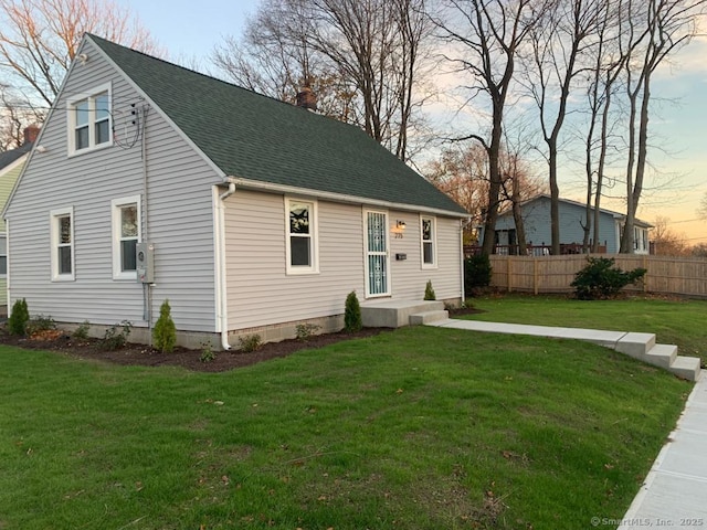view of front facade with a lawn, a chimney, and fence