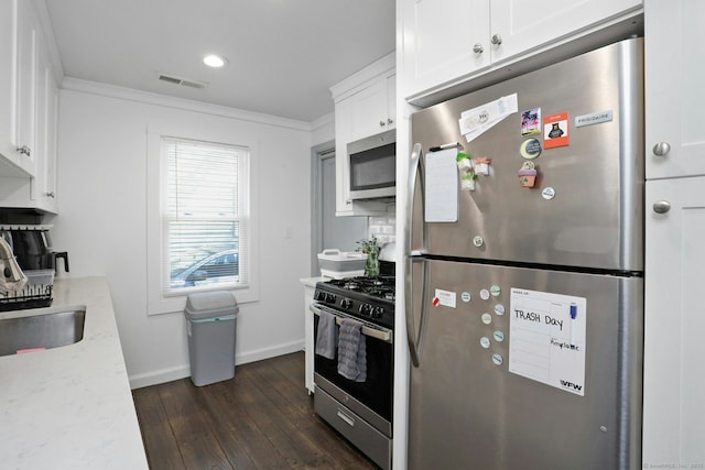 kitchen featuring visible vents, crown molding, stainless steel appliances, white cabinetry, and a sink
