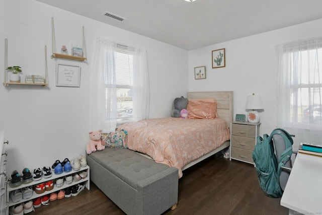 bedroom with dark wood-style floors, visible vents, and multiple windows