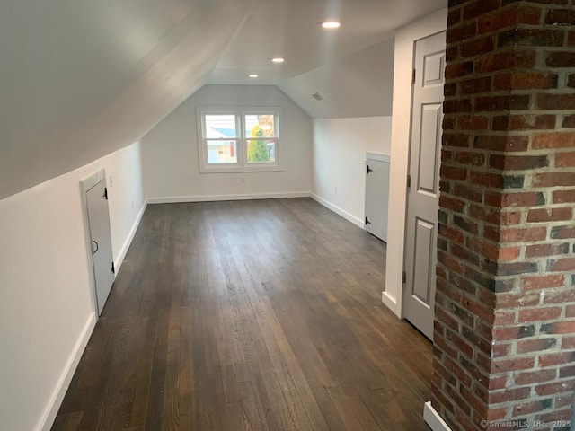additional living space with baseboards, lofted ceiling, and dark wood-style flooring