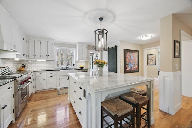 34 Kent Rd, Warren, CT 06754 - kitchen with high end stainless steel range, a sink, light wood-type flooring, and tasteful backsplash