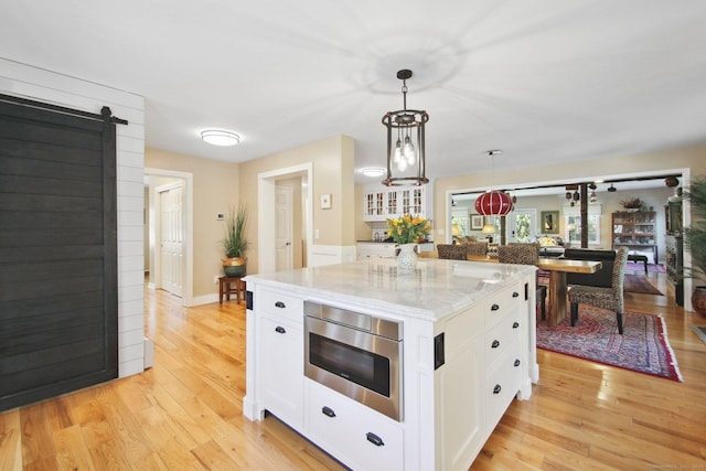 34 Kent Rd, Warren, CT 06754 - kitchen featuring light stone counters, white cabinets, light wood finished floors, hanging light fixtures, and a kitchen island
