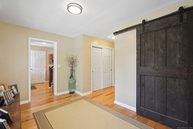 34 Kent Rd, Warren, CT 06754 - bedroom with a barn door, light wood-style floors, baseboards, and a closet