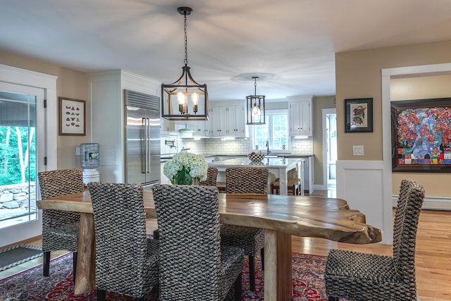 34 Kent Rd, Warren, CT 06754 - dining area with a chandelier, light wood finished floors, a baseboard radiator, and a wainscoted wall