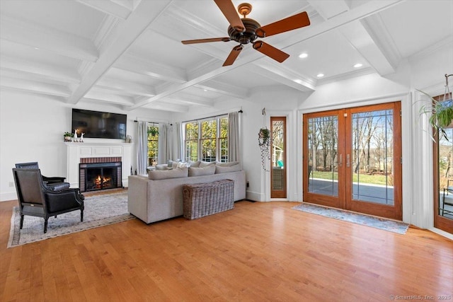 living area featuring french doors, a brick fireplace, beamed ceiling, coffered ceiling, and light wood finished floors