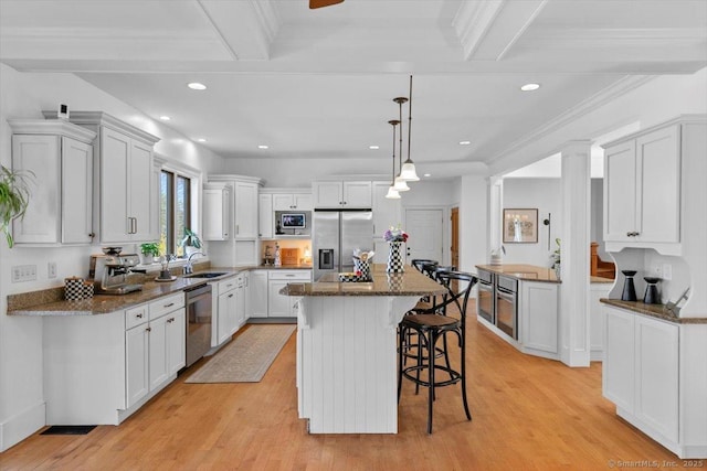 kitchen with white cabinets, a center island, light wood-type flooring, stainless steel appliances, and a breakfast bar area