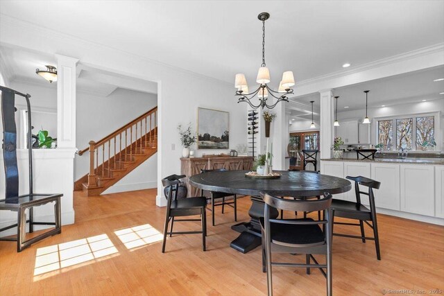 dining area with light wood finished floors, decorative columns, and ornamental molding