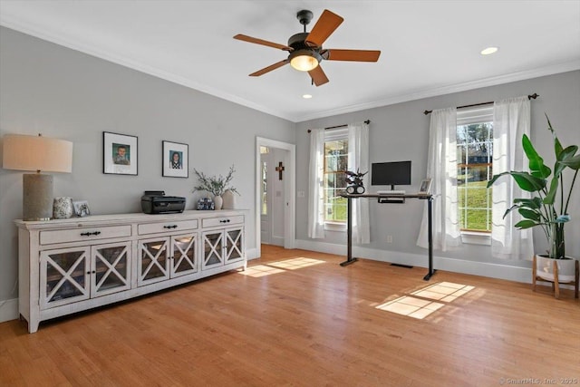 workout area with light wood-type flooring, ornamental molding, and a healthy amount of sunlight