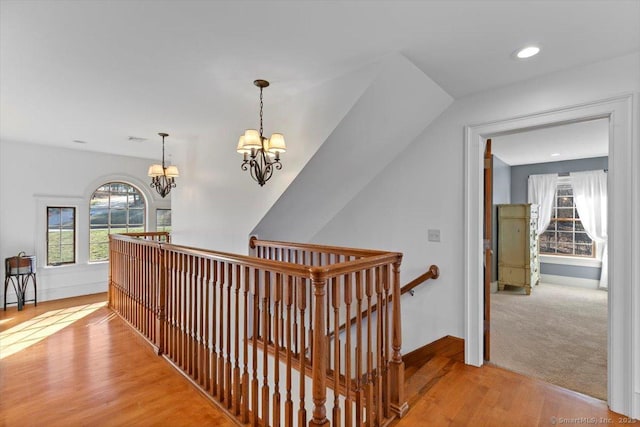 hall featuring baseboards, an inviting chandelier, an upstairs landing, light wood-style floors, and recessed lighting