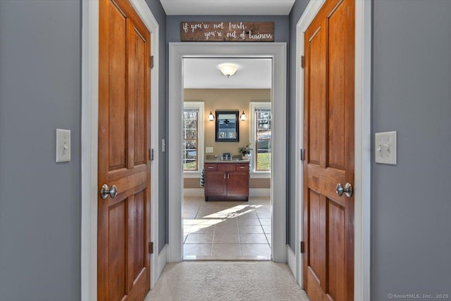hall featuring light tile patterned flooring and light carpet