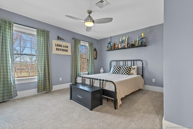 carpeted bedroom with visible vents, multiple windows, baseboards, and ceiling fan