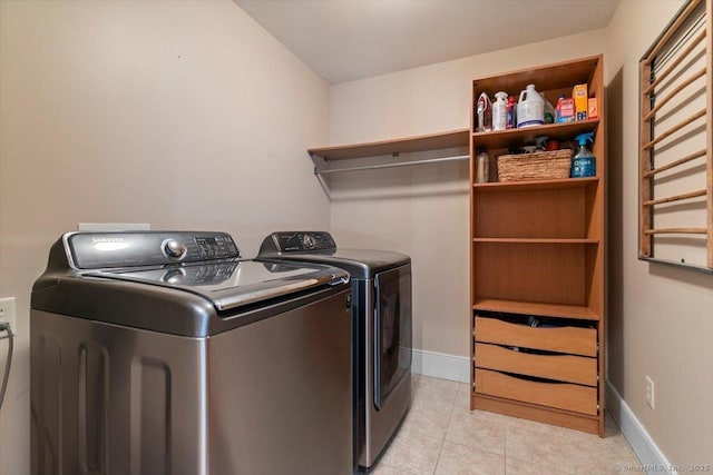 washroom with light tile patterned floors, baseboards, washer and dryer, and laundry area