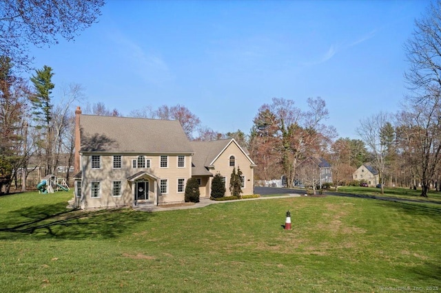 colonial-style house featuring a front yard and a playground