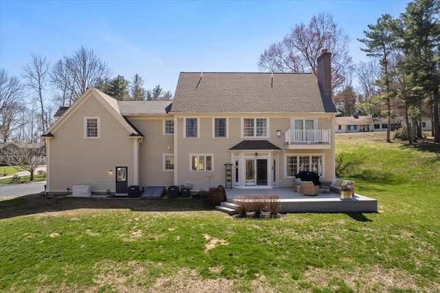 back of property featuring a yard, a chimney, an outdoor hangout area, and a balcony