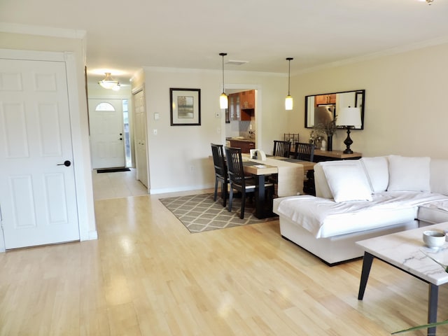 living room with ornamental molding, baseboards, and light wood finished floors