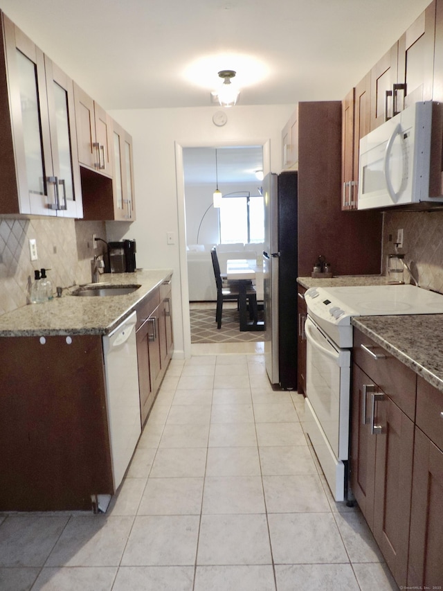 kitchen featuring backsplash, light stone counters, a sink, and white appliances