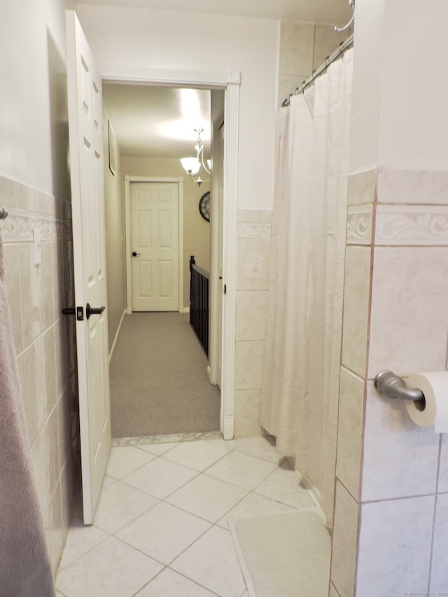 full bathroom featuring a shower with curtain, tile walls, a chandelier, wainscoting, and tile patterned floors