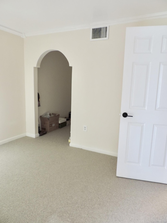 spare room featuring carpet flooring, arched walkways, baseboards, visible vents, and crown molding