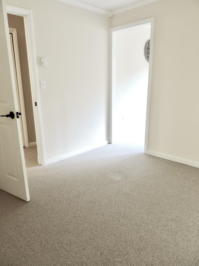 empty room with ornamental molding, carpet floors, and baseboards