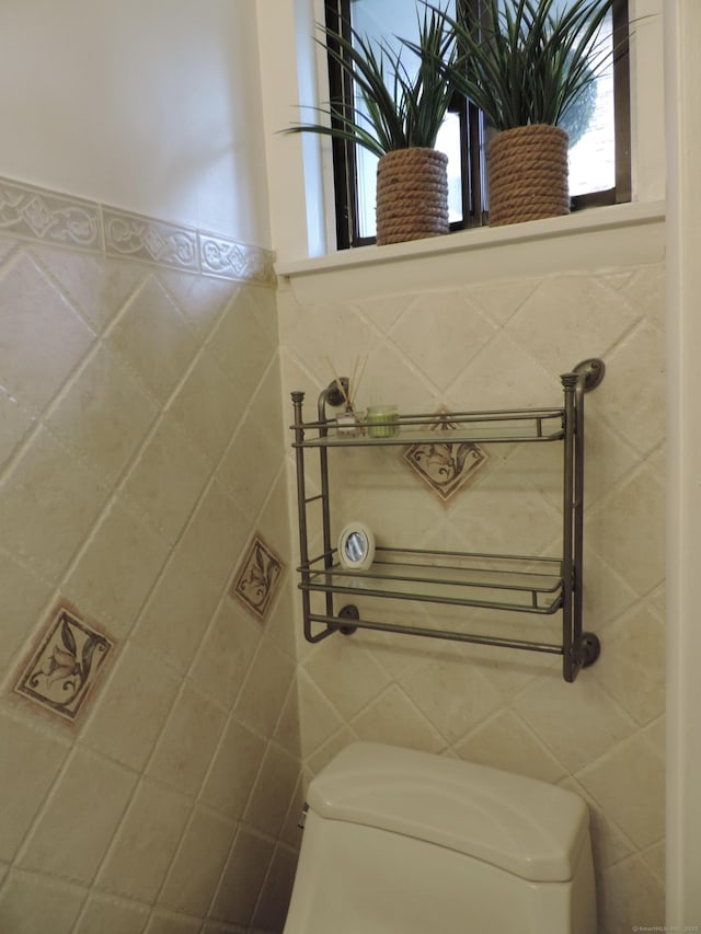bathroom featuring tile walls and toilet