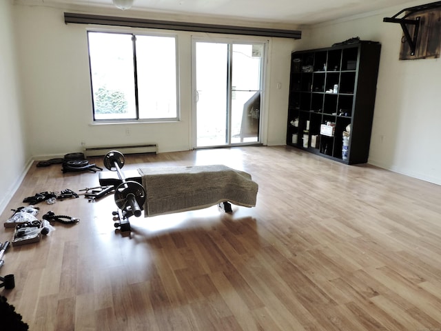 exercise room featuring a baseboard heating unit and wood finished floors