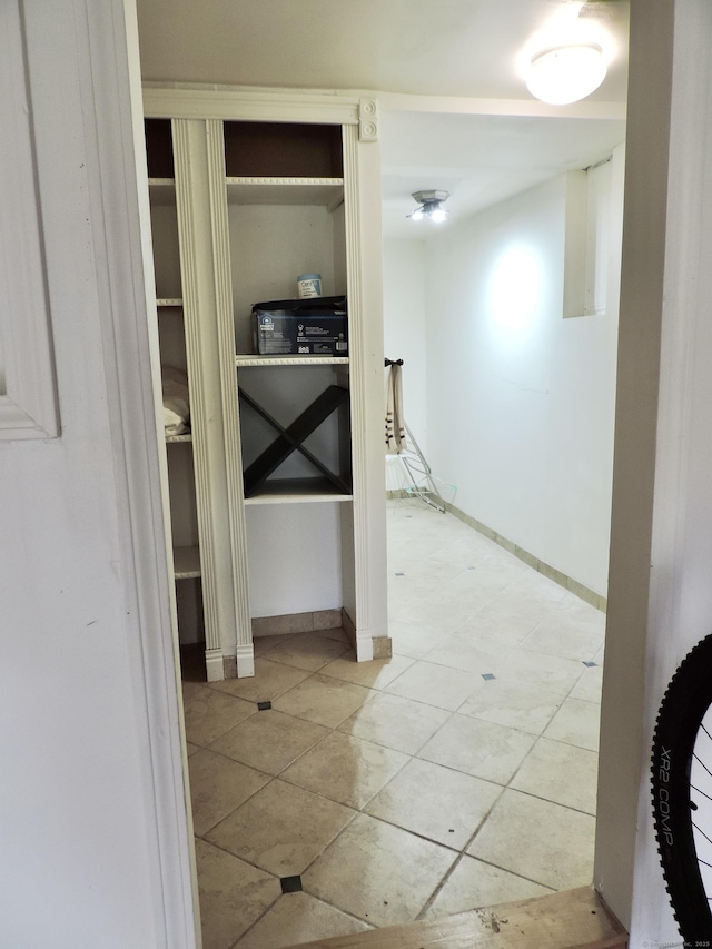 hallway with tile patterned floors and baseboards