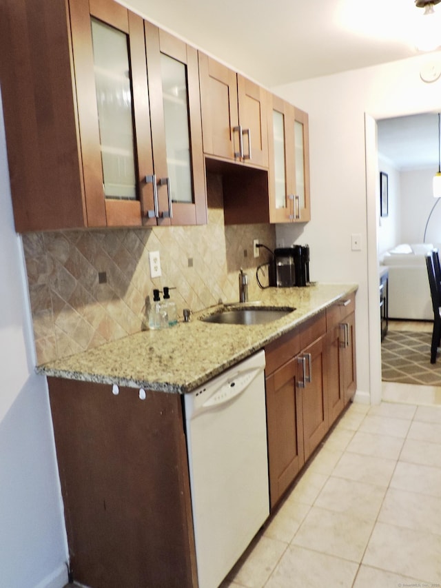 kitchen with light stone counters, glass insert cabinets, decorative backsplash, white dishwasher, and a sink
