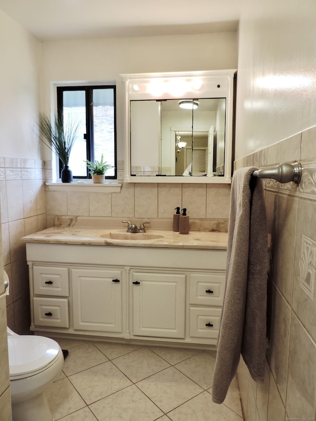 bathroom featuring tile patterned floors, vanity, tile walls, and toilet