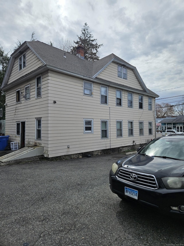 view of side of home featuring a gambrel roof and a chimney