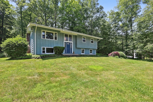 36 Musket Ridge Rd, New Fairfield, CT 06812 - bi-level home with board and batten siding, a front yard, view of scattered trees, and a wall unit AC