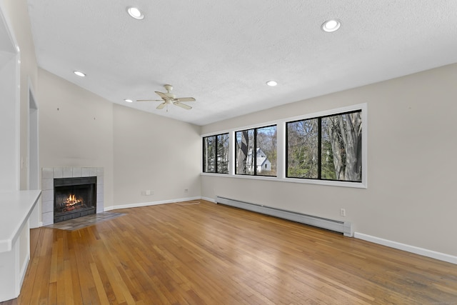 285 Greens Farms Rd, Westport, CT 06880 - unfurnished living room featuring a baseboard heating unit, a textured ceiling, a ceiling fan, light wood finished floors, and a tiled fireplace