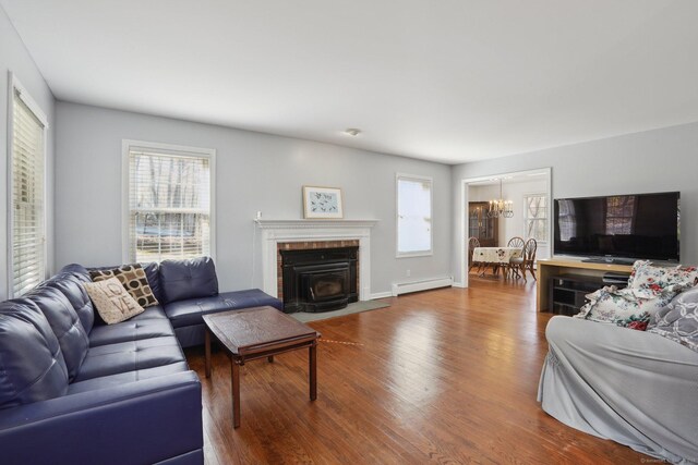 living area with plenty of natural light, an inviting chandelier, wood finished floors, and a baseboard radiator