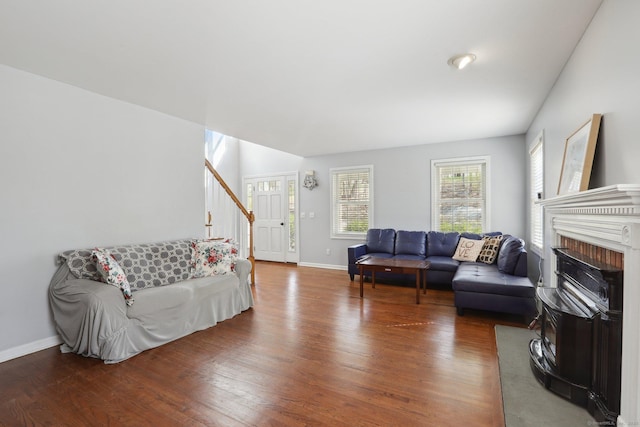 living room featuring a fireplace, wood finished floors, baseboards, and stairs