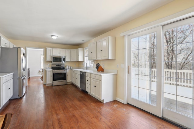 kitchen featuring stainless steel appliances, light countertops, dark wood-style floors, and a sink