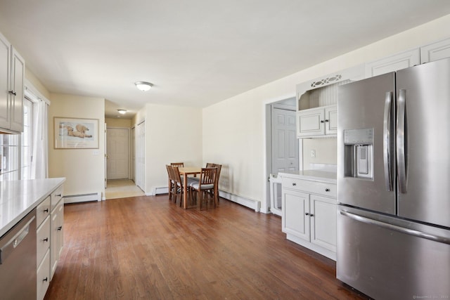 kitchen featuring appliances with stainless steel finishes, light countertops, baseboard heating, white cabinets, and dark wood-style flooring
