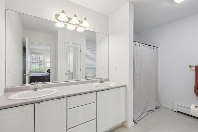 ensuite bathroom featuring double vanity, a sink, connected bathroom, and a baseboard radiator