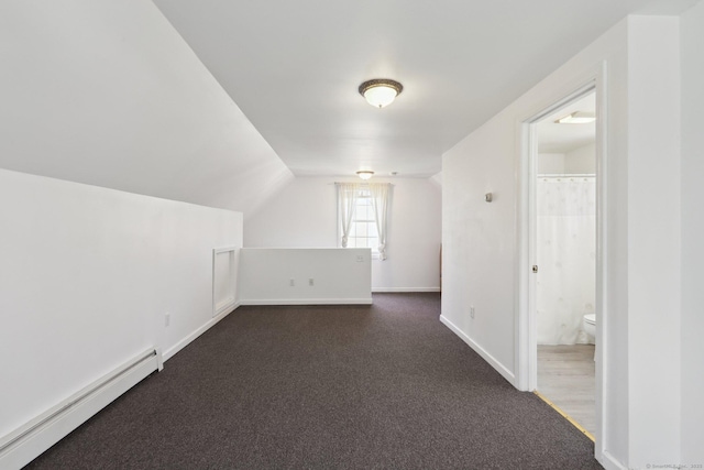 additional living space featuring baseboard heating, baseboards, dark carpet, and vaulted ceiling