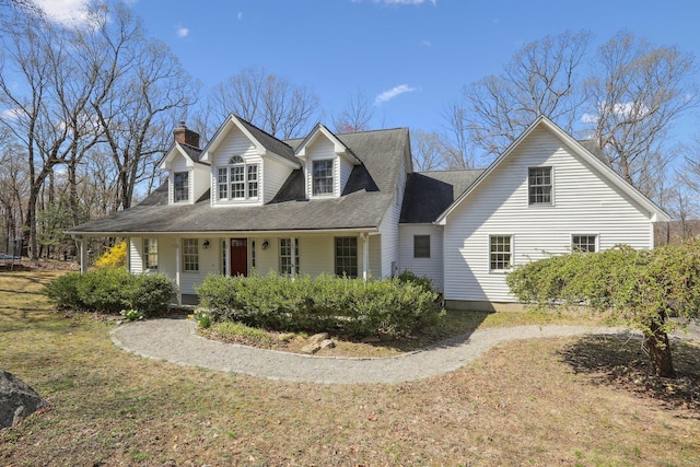 cape cod house with a chimney and covered porch