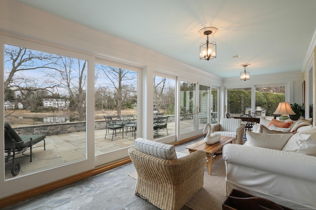 sunroom with stone finish floor, french doors, an inviting chandelier, and a healthy amount of sunlight