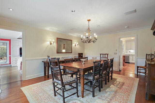 dining space with wood finished floors, an inviting chandelier, and ornamental molding