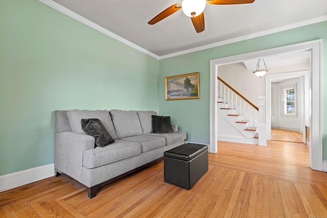 living area featuring crown molding, a ceiling fan, stairs, and baseboards