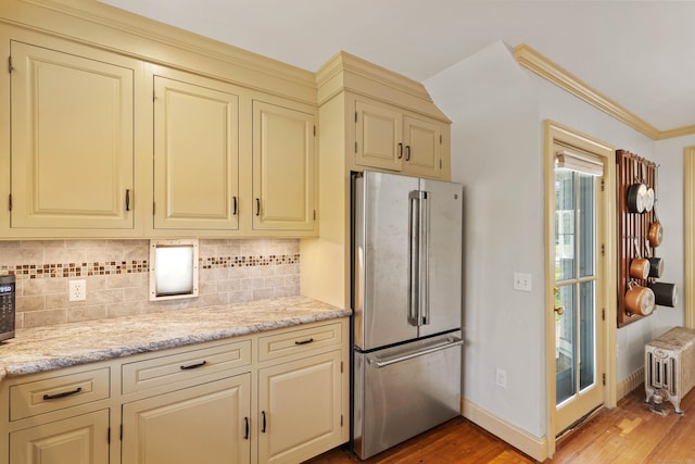 kitchen with light wood-style flooring, cream cabinetry, radiator heating unit, and freestanding refrigerator