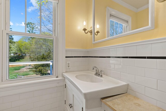 bathroom with vanity, a wainscoted wall, ornamental molding, and tile walls