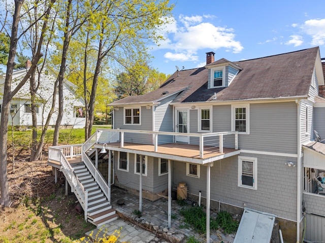 back of property featuring a chimney, stairs, a shingled roof, and a wooden deck