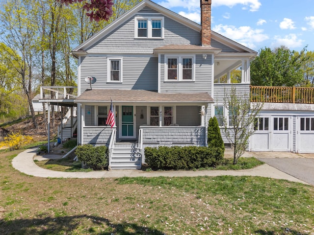 traditional style home featuring a chimney, covered porch, a front lawn, and stairs