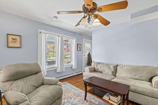 living area featuring baseboard heating, wood finished floors, and a ceiling fan