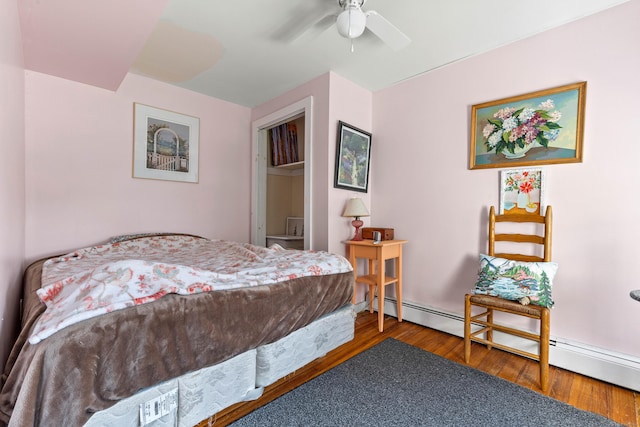 bedroom with ceiling fan, wood finished floors, and a baseboard radiator